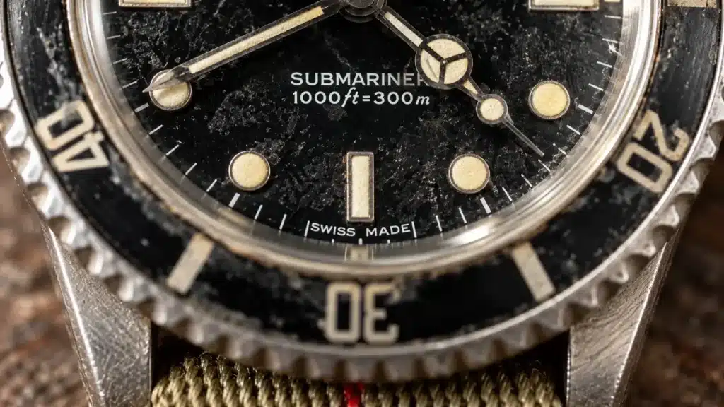 La scritta SWISS MADE a ore 6 identifica la 14060M a due righe. Immagine illustrativa. Macro della parte bassa di un quadrante Submariner con scritta 1000ft=300m e SWISS MADE a ore 6